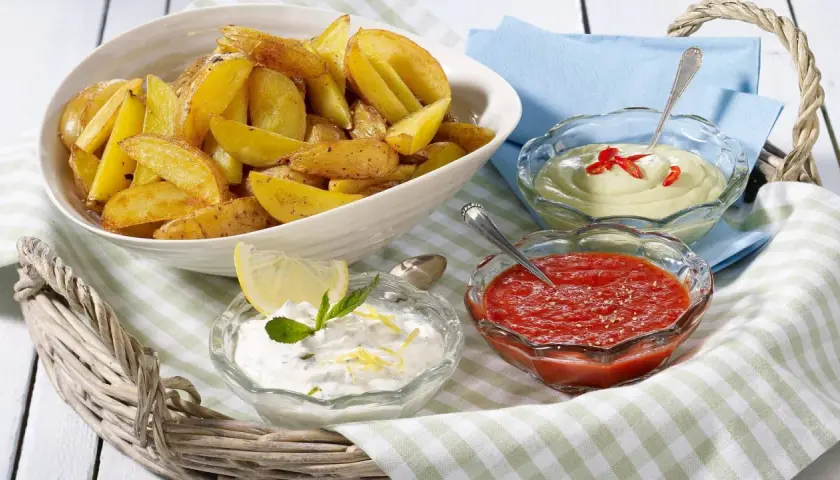 Knusprige Kartoffelecken mit drei Dips: ein cremiger Dip mit Chili, ein roter Dip und ein Joghurt-Dip mit Zitrone und Minze. Perfekt zum Teilen!