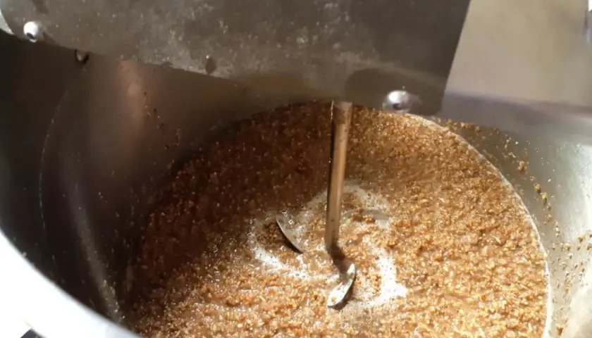 Ein Rührwerk mischt Malzschrot in einem Kessel für die Bierinfusion.