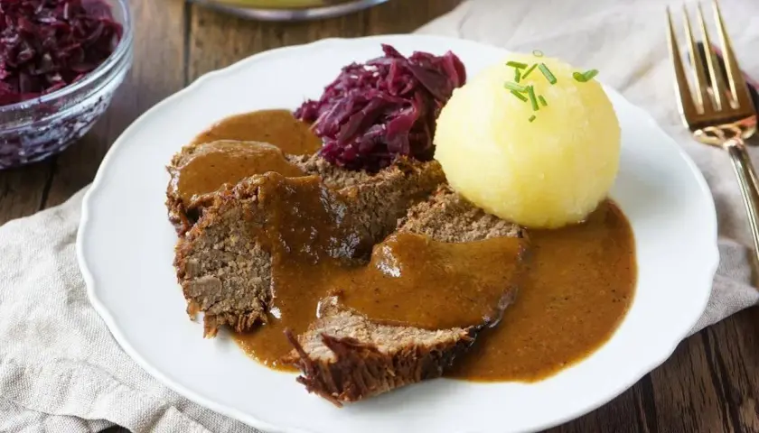 Herzhaftes falsches Filet Sauerbraten mit Klößen und Rotkohl, übergossen mit dunkler Soße.