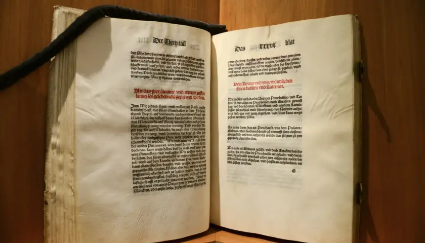 Altes Buch mit lateinischem Text. Ein schwarzes Band hält die Seiten zusammen. Das **deutsche Reinheitsgebot** von 1516 wird hier in alter Schrift zitiert.
