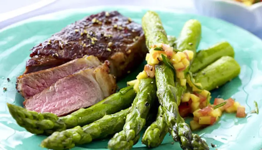 Saftiger Rumpsteak in der Pfanne, medium gebraten, serviert mit grünem Spargel und einer fruchtigen Salsa.