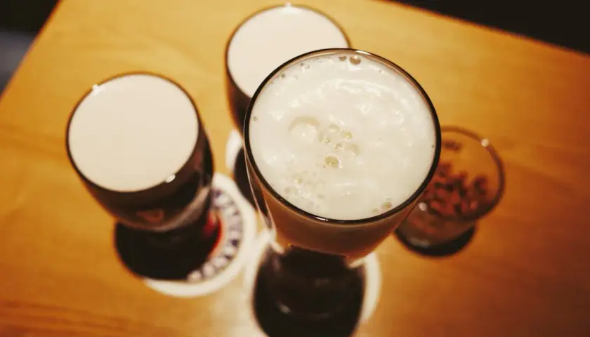 Drei Gläser mit Schaumkrone und ein Glas mit Nüssen – perfekte blindverkostung ideen für einen gemütlichen Abend.