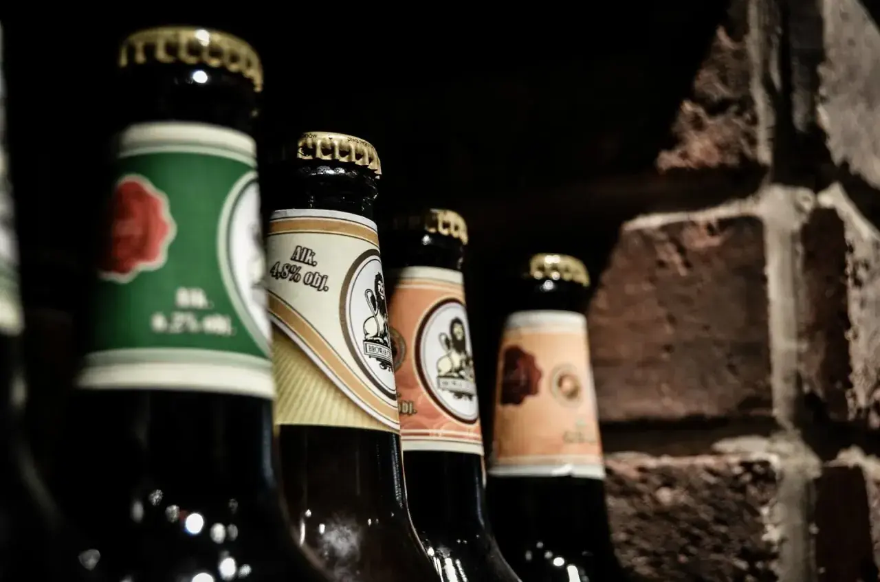 Mehrere Bierflaschen stehen nebeneinander, bereit zum Bier lagern. Die Etiketten zeigen verschiedene Designs und Alkoholprozente.