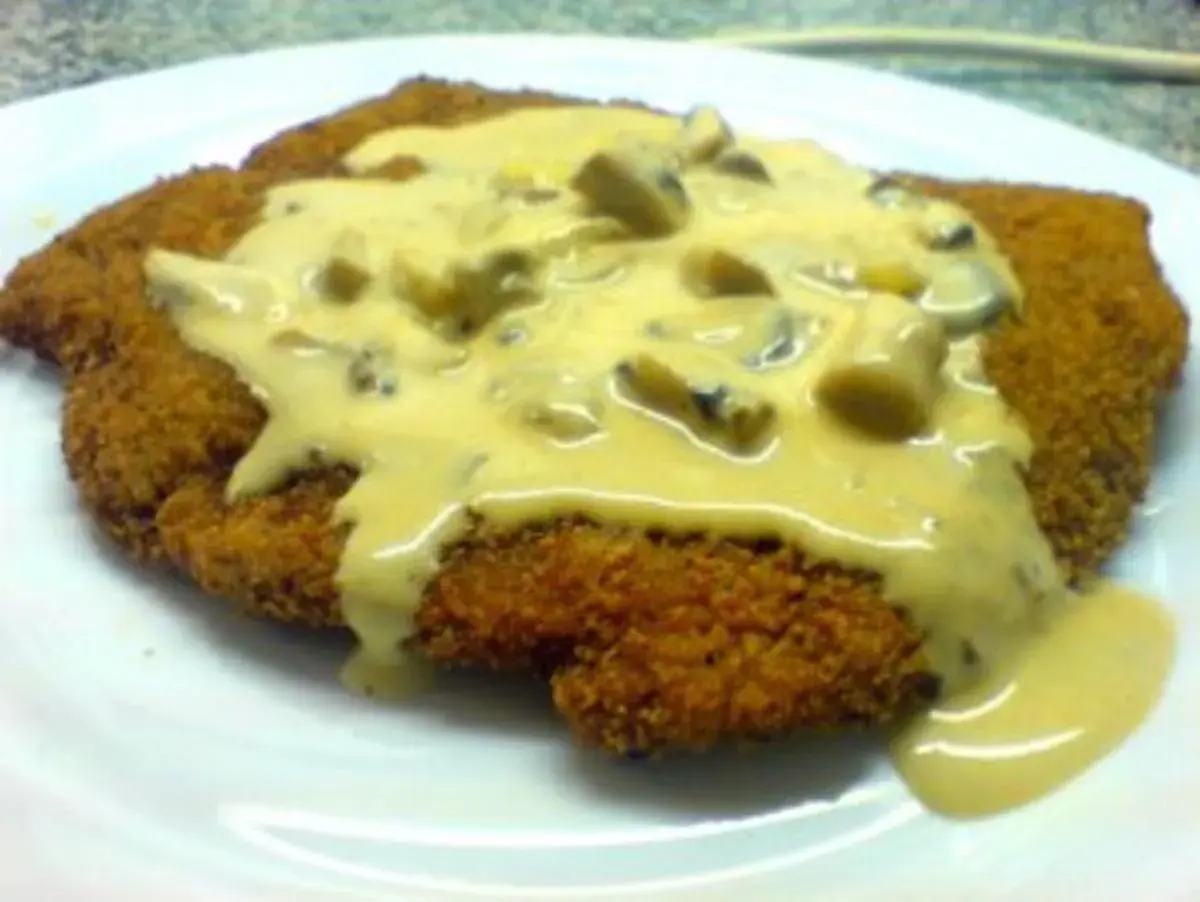 Ein knuspriges Schnitzel, bedeckt mit einer cremigen Pilzsoße, wie vom Braumeister serviert.