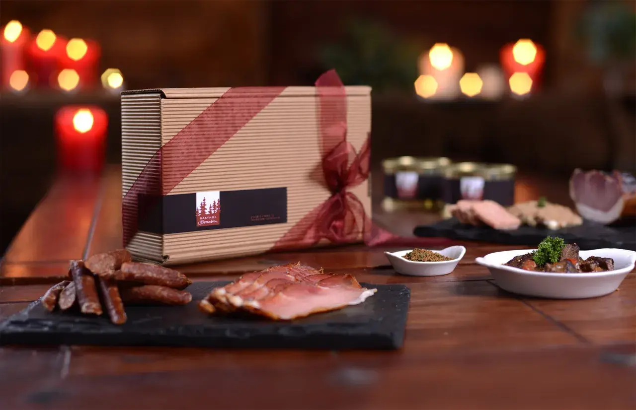 Geschenkbox mit Wurstwaren und Pastete, dazu ein Glas mit Gewürzen und ein Gericht mit Fleisch. Perfekt zu einem Glas **amber ale**.