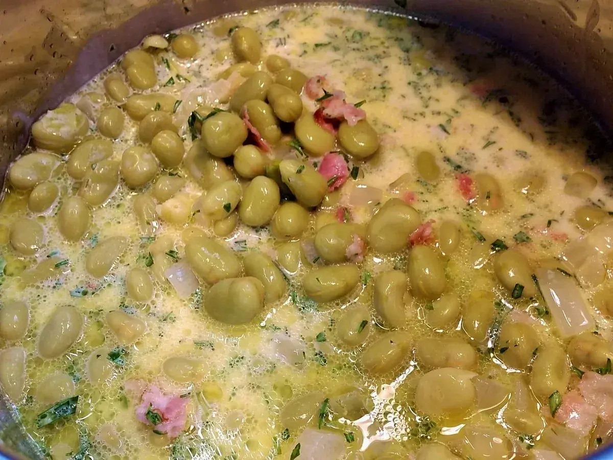 Dicke Bohnen werden in einer cremigen Sauce mit Speck und Kräutern zubereitet. Ein köstliches Gericht, das zum Genießen einlädt.