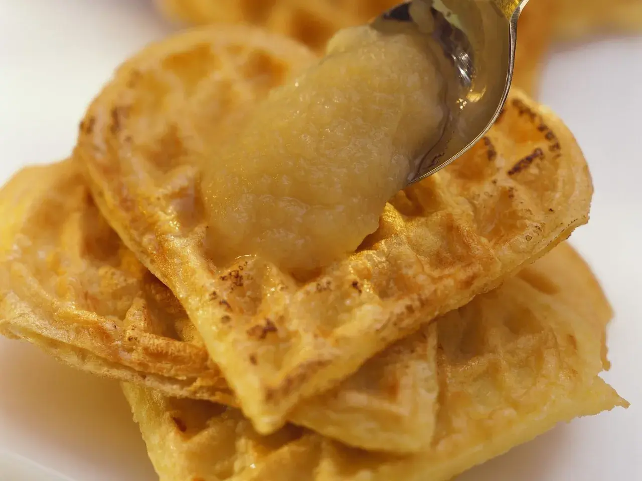 Goldbraune Waffeln, gestapelt und mit einem Löffel Apfelmus bedeckt. Ein süßer Genuss!