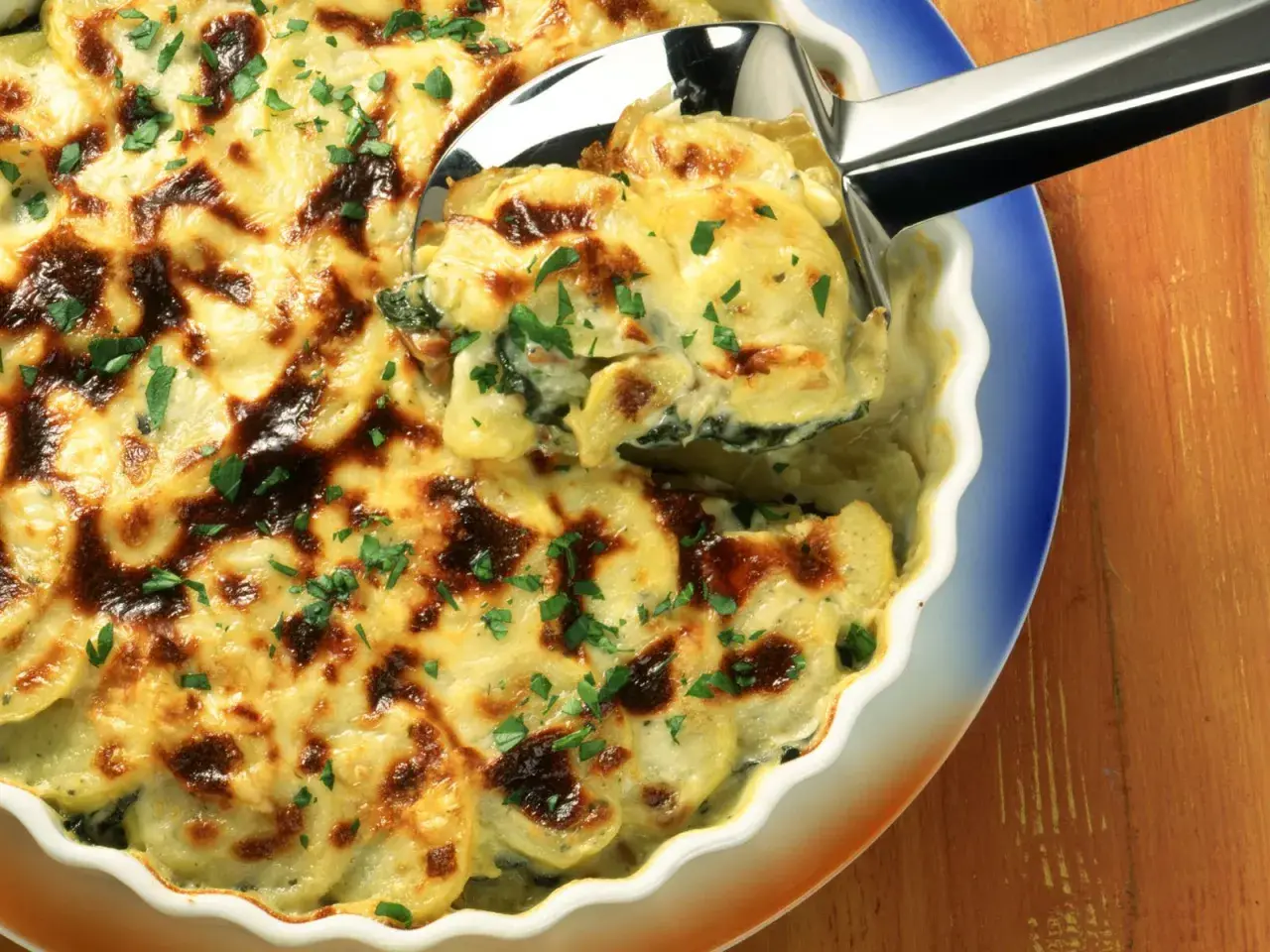 Herzhaftes Mangold-Kartoffel-Gratin mit goldbrauner Käsekruste, garniert mit frischer Petersilie. Ein köstliches Rezept!