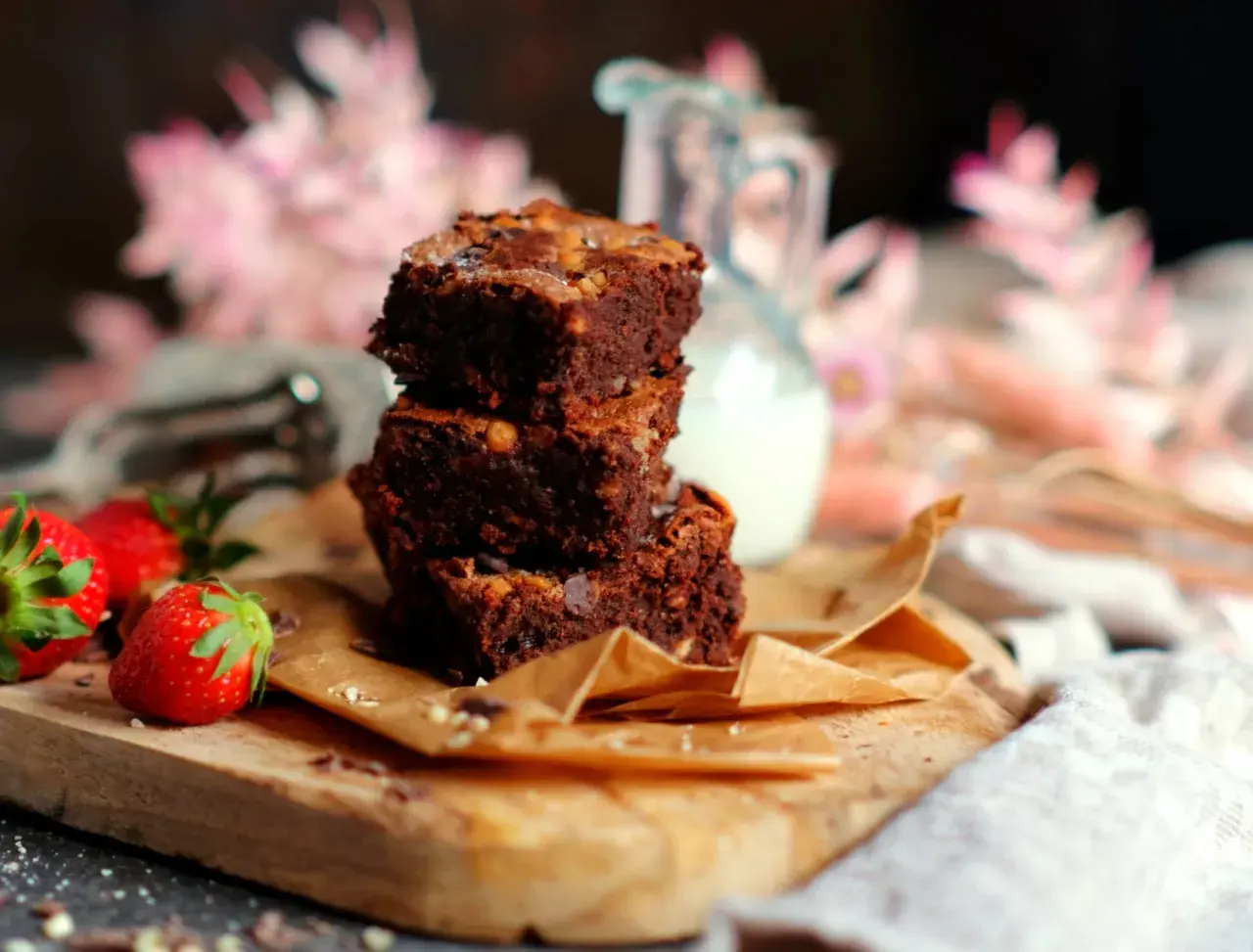 Gestapelte Brownies auf einem Holzbrett, daneben Erdbeeren. Ein tolles brownie rezept ohne schokolade für Naschkatzen.