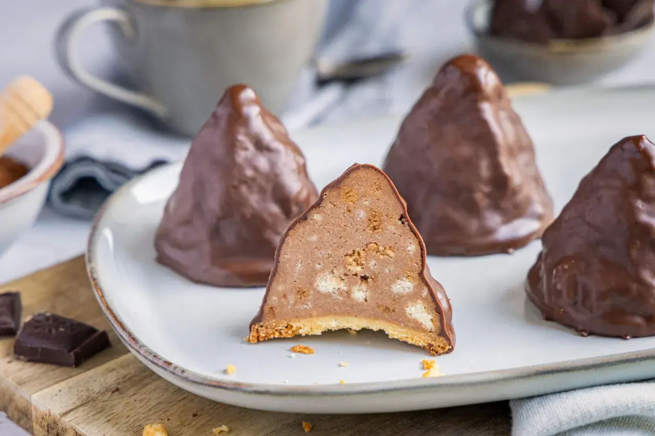 Schokoladen-Desserts, die an Granatsplitter erinnern, auf einem Teller. Ein Stück ist angeschnitten und zeigt die cremige Füllung mit Keksstückchen. Ein tolles granatsplitter rezept.