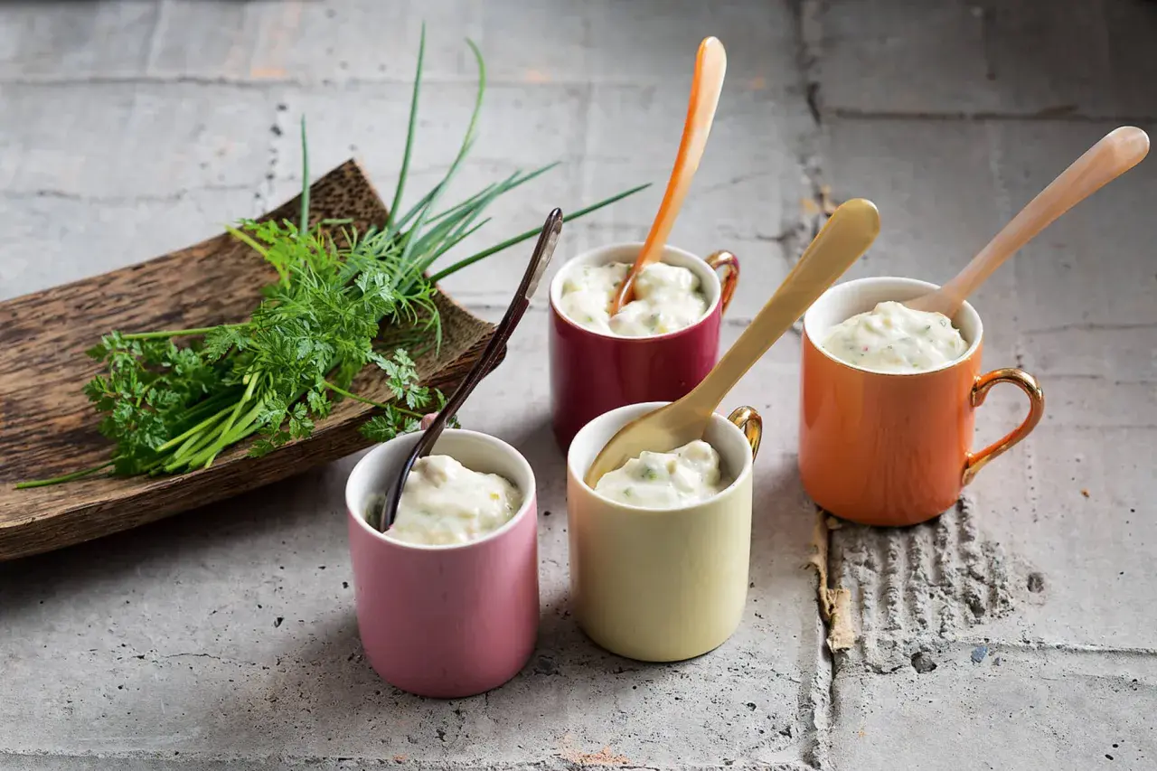 Vier bunte Tassen mit cremiger Remoulade, dazu frische Kräuter. Ein einfaches Remoulade Rezept zum Nachmachen.