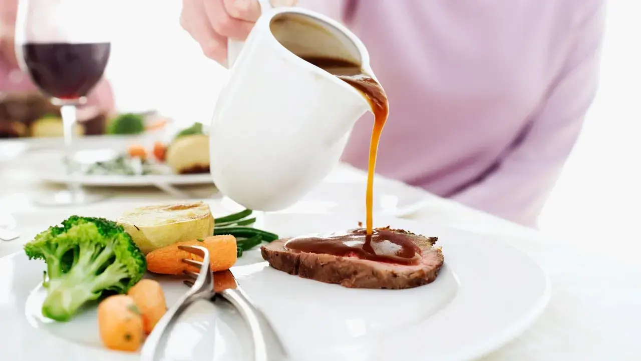 Eine Person übergießt ein Roastbeef mit Soße. Dazu gibt es Brokkoli, Karotten und Kartoffeln. Perfekt zum Fond kochen!