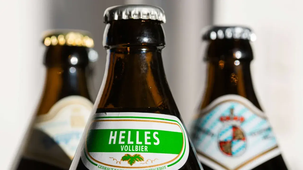 Drei Bierflaschen, eine mit "Helles Vollbier" beschriftet. Der Unterschied zwischen Vollbier und hellem Bier wird hier visuell angedeutet.