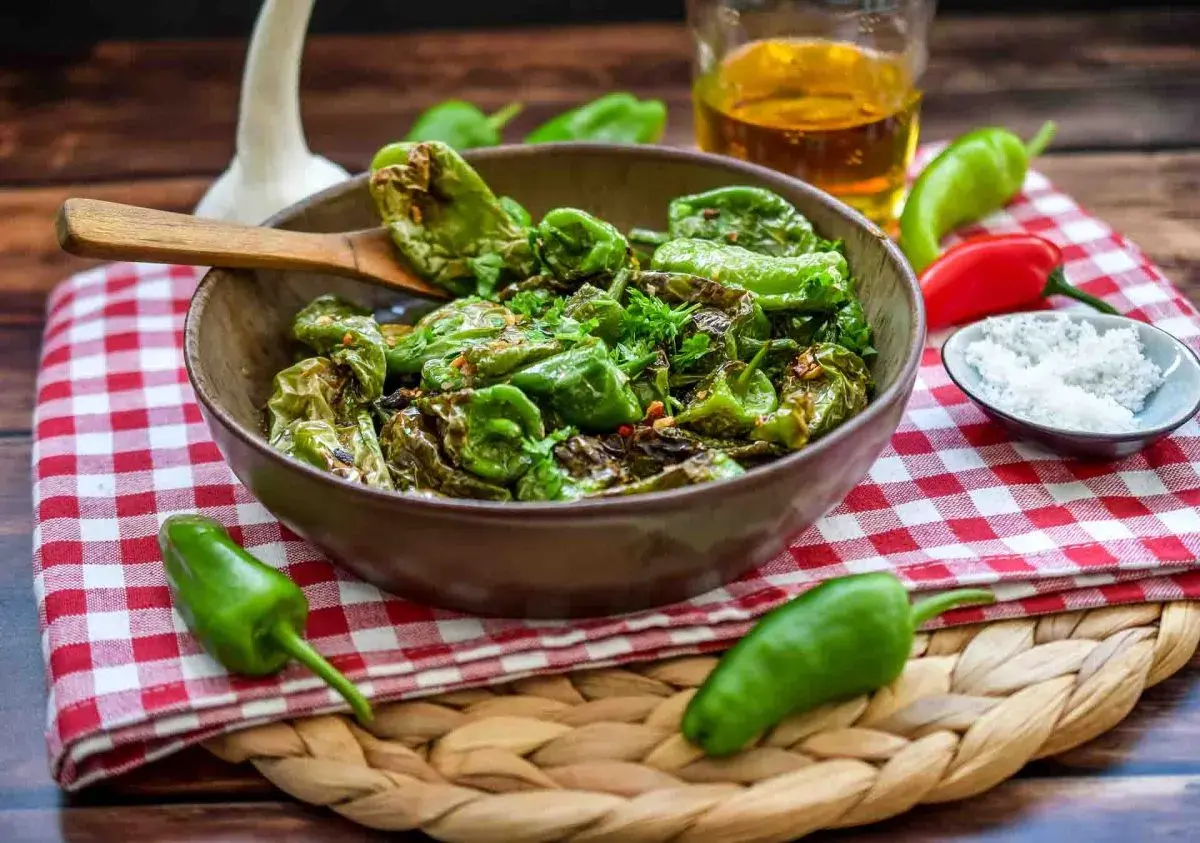 Gebratene Pimientos de Padrón, ein einfaches und leckeres Rezept. Mit grobem Salz bestreut, serviert mit Olivenöl und frischen Kräutern.