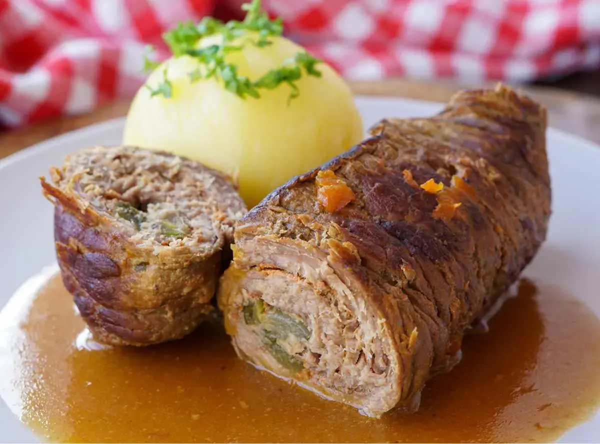 Saftige Rinderrouladen mit einer Füllung aus Hackfleisch und Gemüse, serviert mit Kartoffelklößen und einer köstlichen Soße.