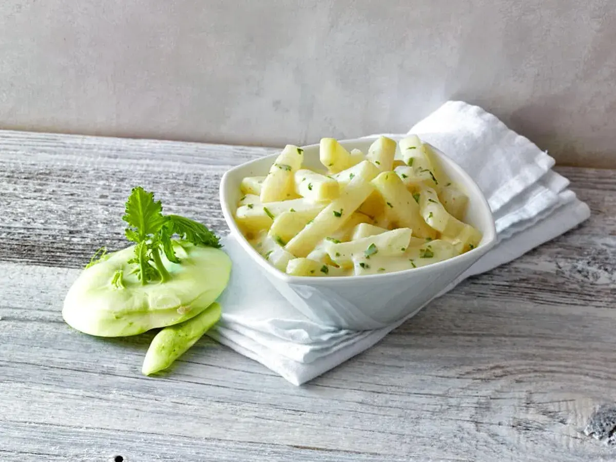 Kohlrabi in cremiger Sauce, bereit für die Kochzeit. Daneben ein frischer Kohlrabi mit Grün.