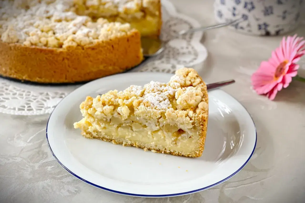 Ein Stück saftiger versunkener Apfelkuchen mit Pudding und Streuseln, bestäubt mit Puderzucker.