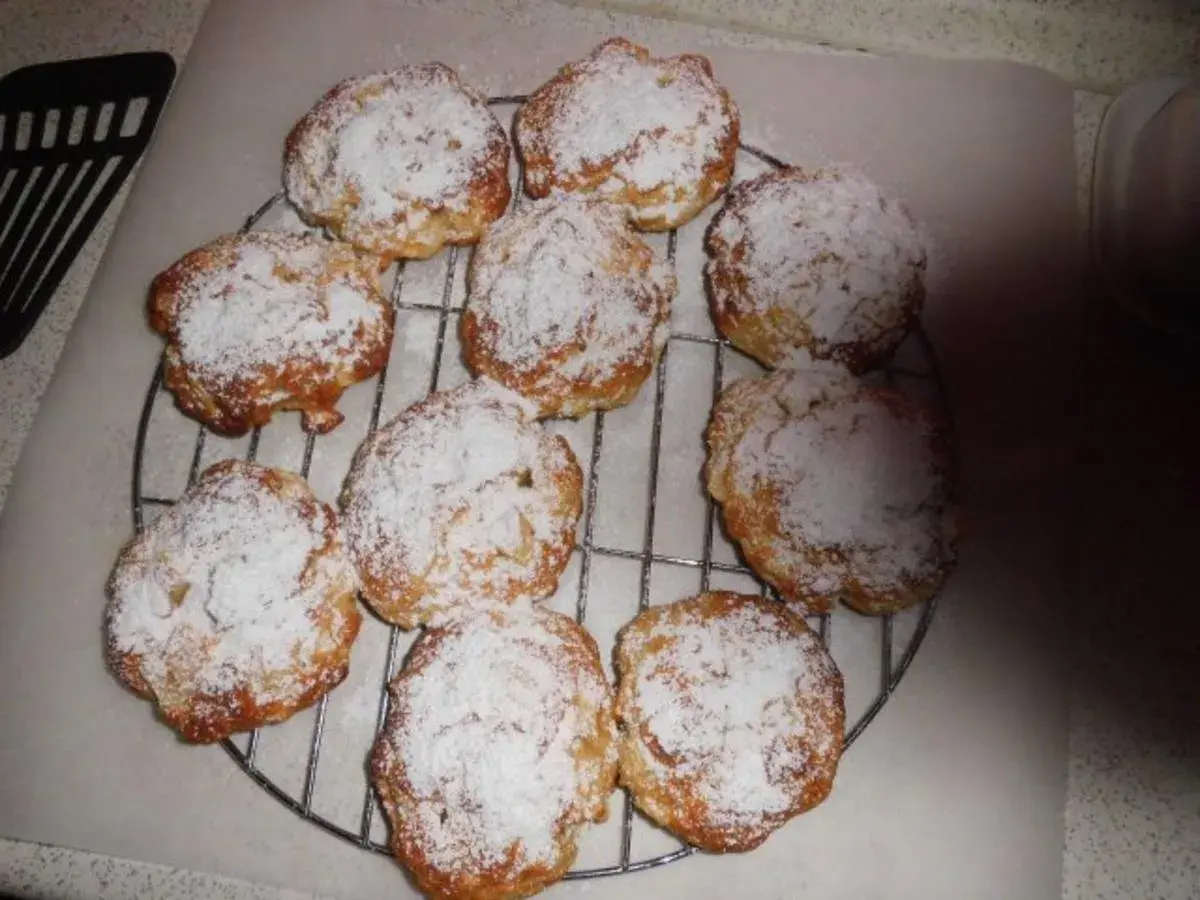 Saftige Apfeltaler mit Quark, bestäubt mit Puderzucker, auf einem Kuchengitter.
