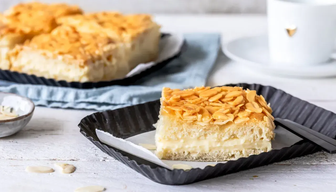 Ein Stück vom Blechkuchen-Bienenstich-Rezept, mit cremiger Füllung und knusprigen Mandeln.