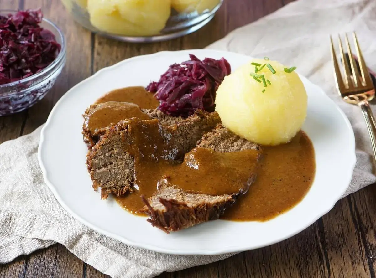 Herzhaftes falsches Filet Sauerbraten mit Klößen und Rotkohl, übergossen mit dunkler Soße.