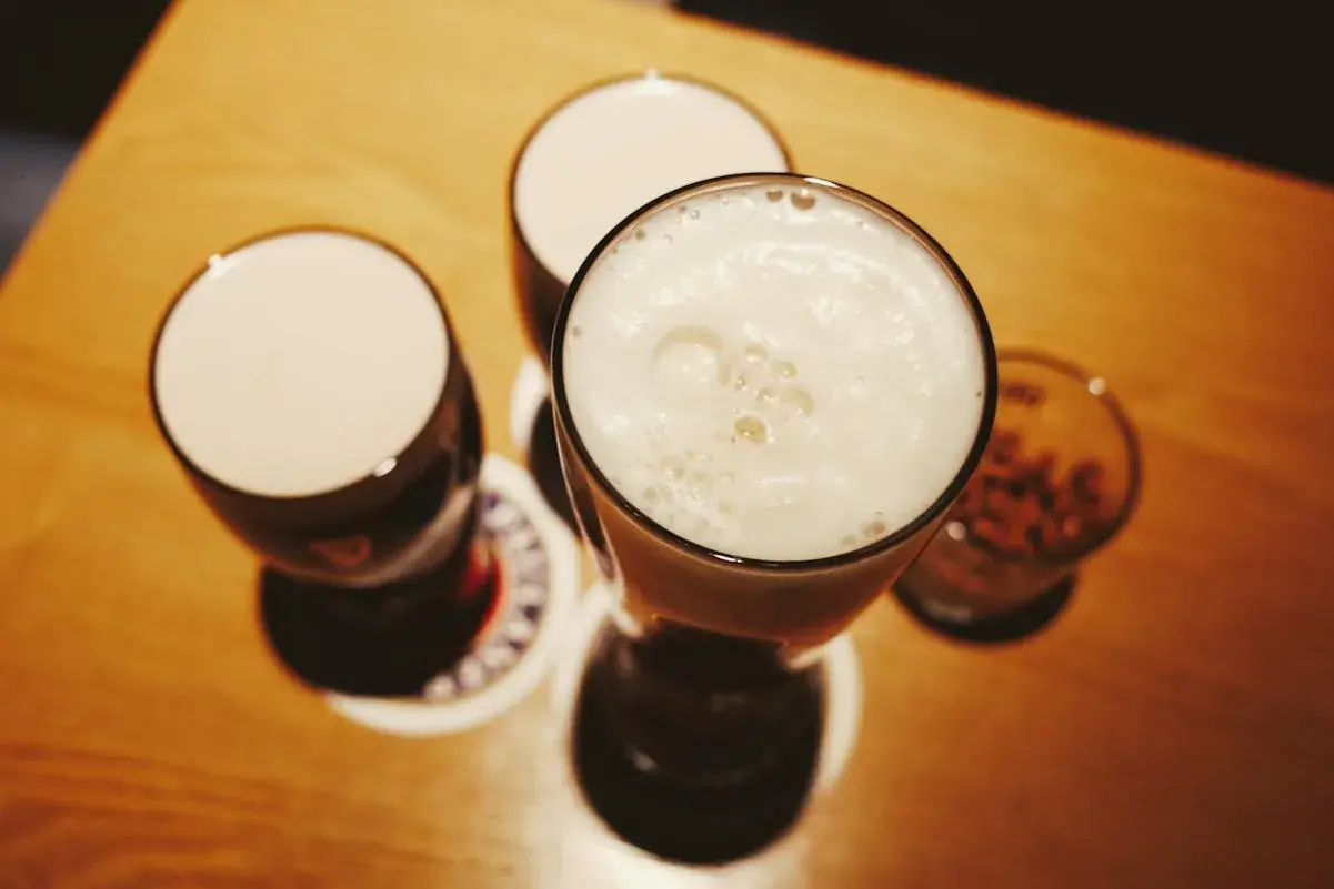 Drei Gläser mit Schaumkrone und ein Glas mit Nüssen – perfekte blindverkostung ideen für einen gemütlichen Abend.