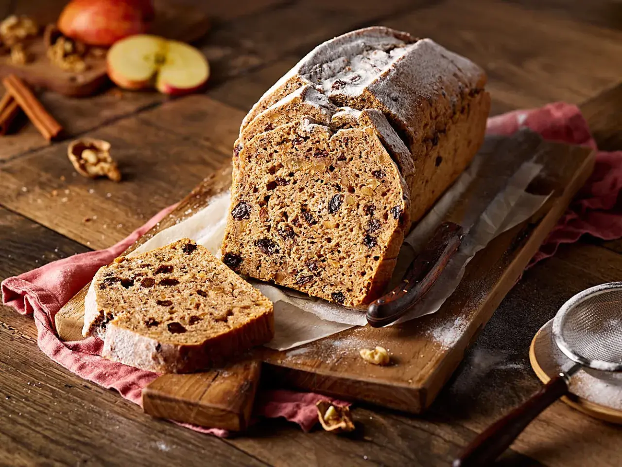 Ein saftiges Apfelbrot mit Rosinen und Nüssen, bestäubt mit Puderzucker. Perfekt für ein gemütliches Apfelbrot Rezept.