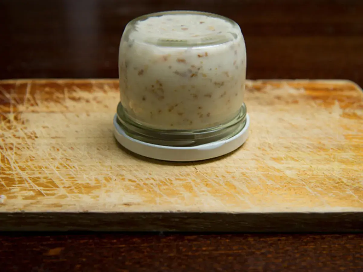 Glas mit Griebenschmalz, bereit für das Griebenschmalz Rezept. Auf einem Holzbrett.