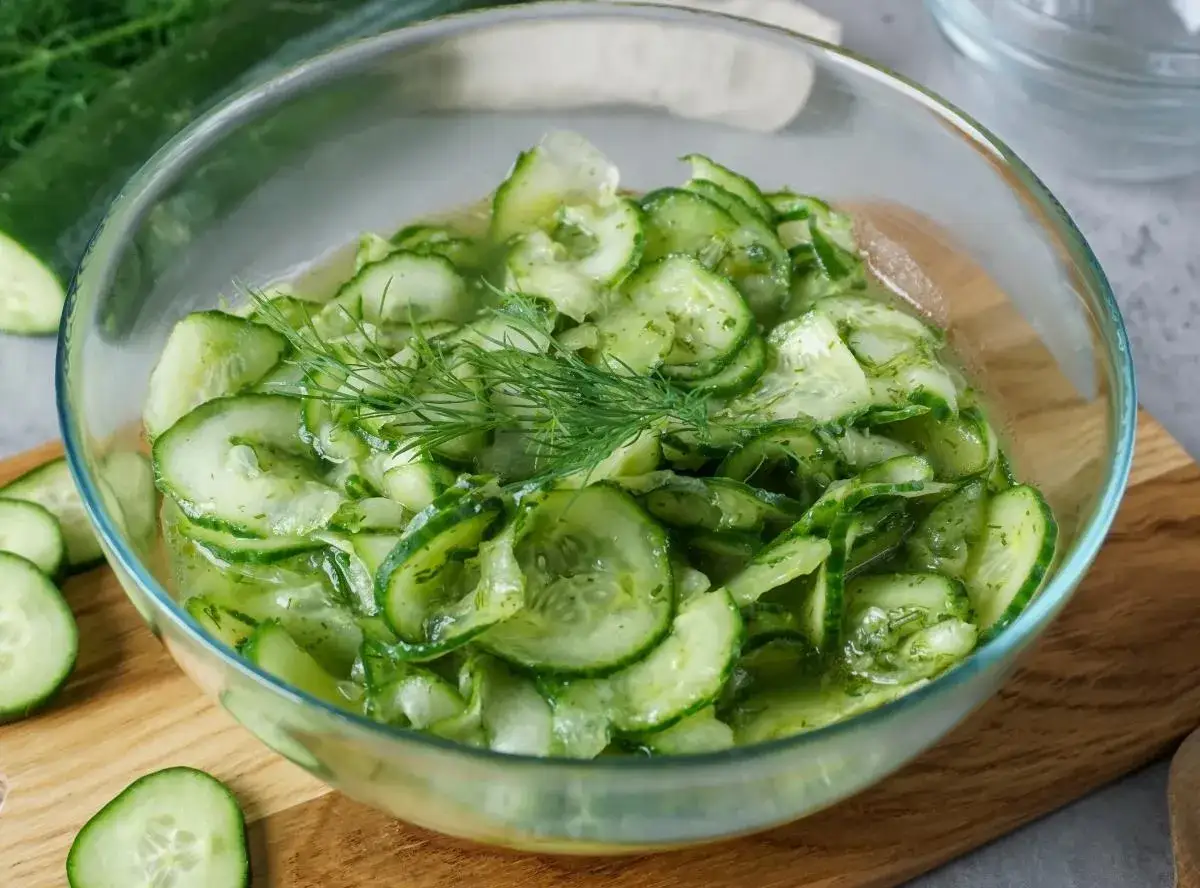 Frischer Gurkensalat, zubereitet durch Gurke raspeln, in einer Glasschüssel mit Dill garniert.