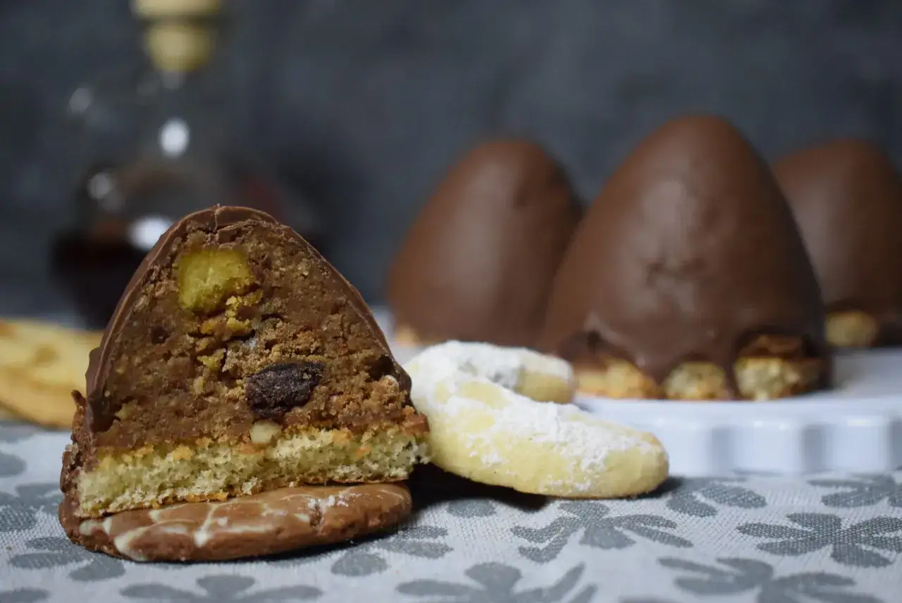 S&uuml;&szlig;e Versuchung: Ein angeschnittener Schoko-Keks mit N&uuml;ssen und Rosinen, daneben Vanillekipferl. Ein leckeres granatsplitter rezept.