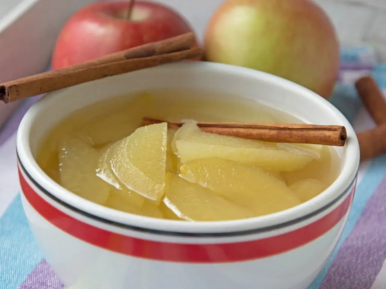 Schon probiert, Apfelkompott selber machen? Hier ist ein k&ouml;stliches Ergebnis: weiche Apfelst&uuml;cke in Sirup mit Zimtstangen, garniert mit frischen &Auml;pfeln.