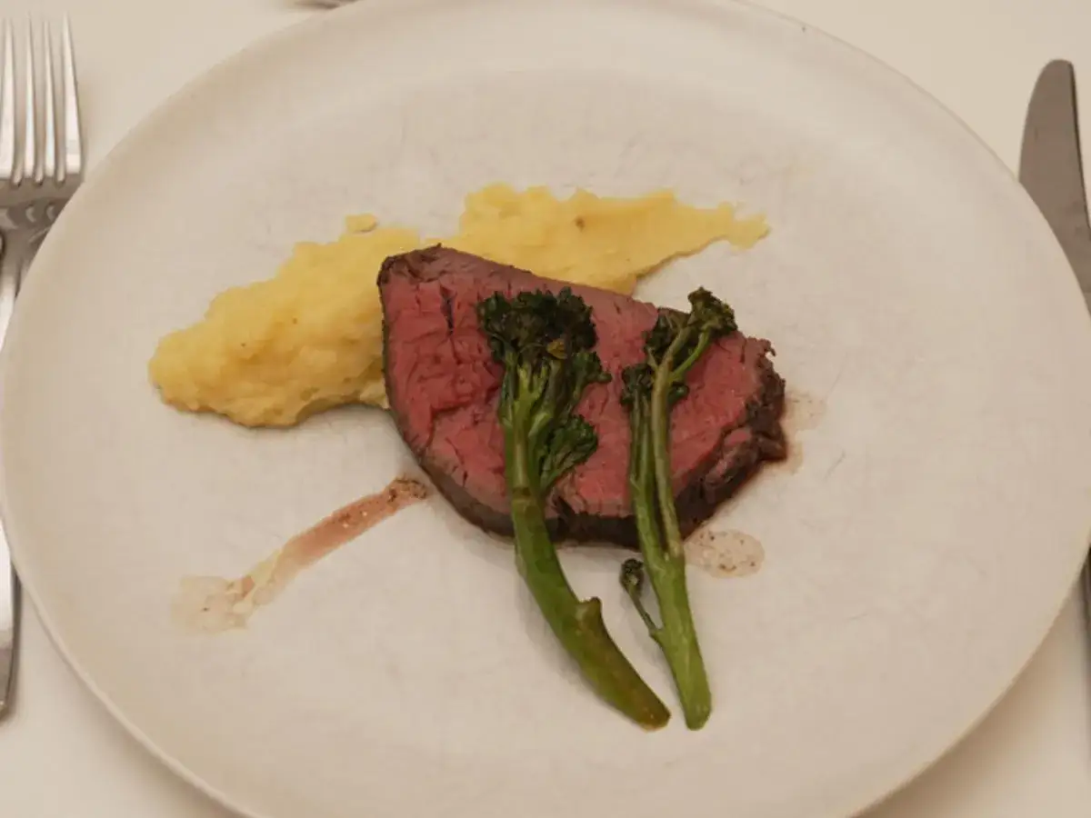 Gebeiztes Rinderfilet mit cremiger Kartoffelbeilage und zartem Brokkoli auf einem rustikalen Teller.