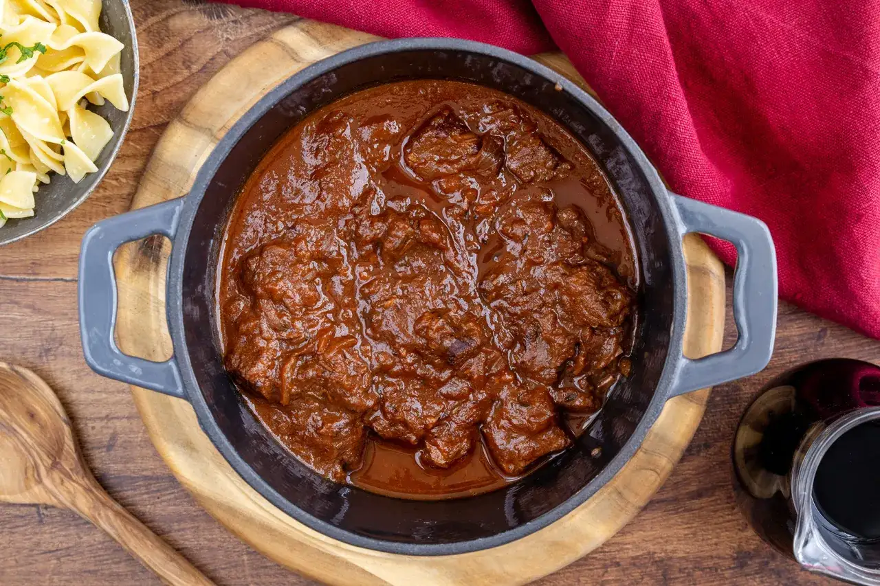 Herzhaftes Gulasch, das Fleisch wurde mariniert und schmort nun in einer dunklen Sauce. Dazu gibt es breite Nudeln.