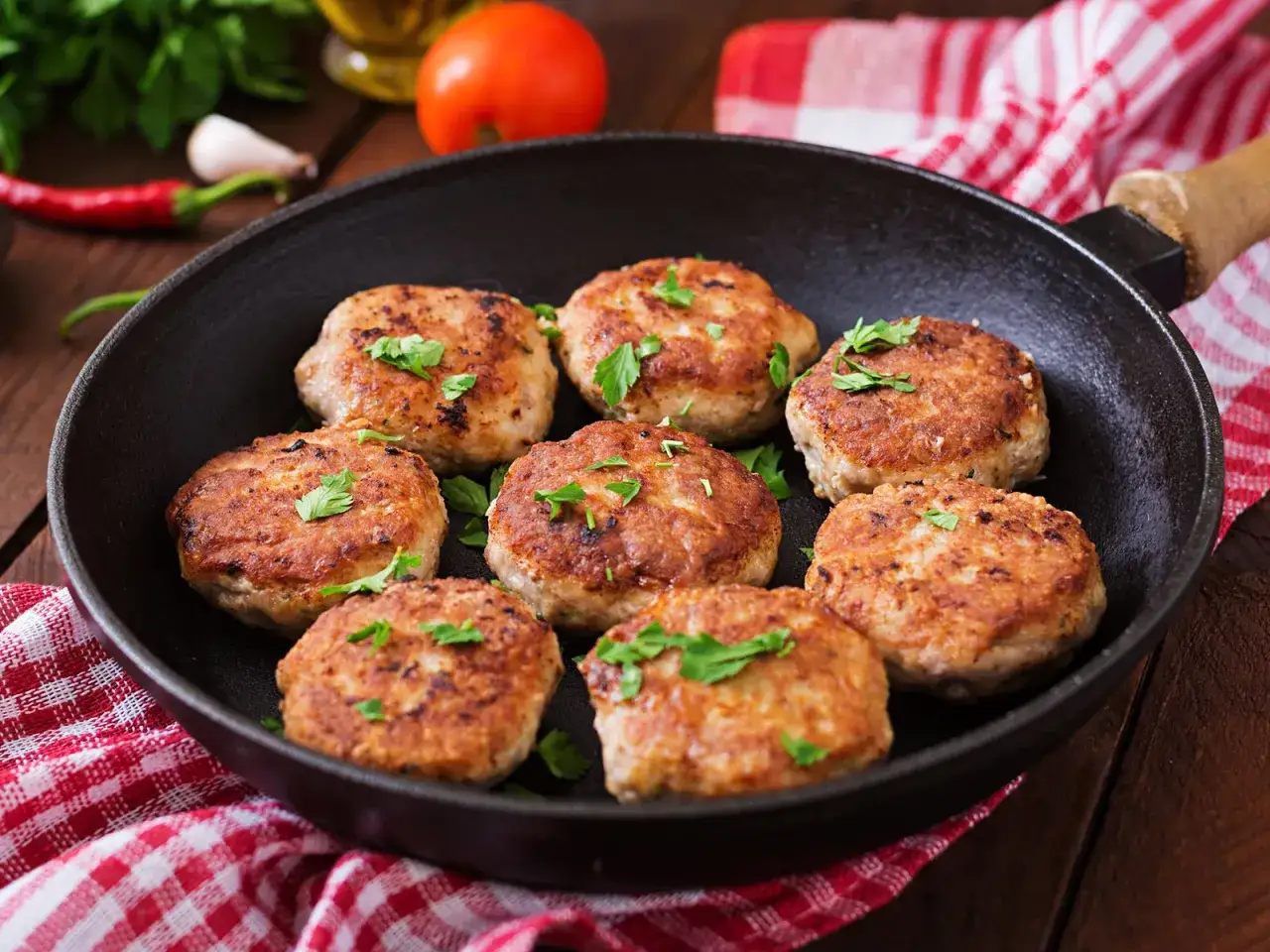 Hei&szlig; gebratene, goldbraune Frikadellen in einer Pfanne, garniert mit Petersilie. Das sind die besten Frikadellen f&uuml;r ein herzhaftes Essen.