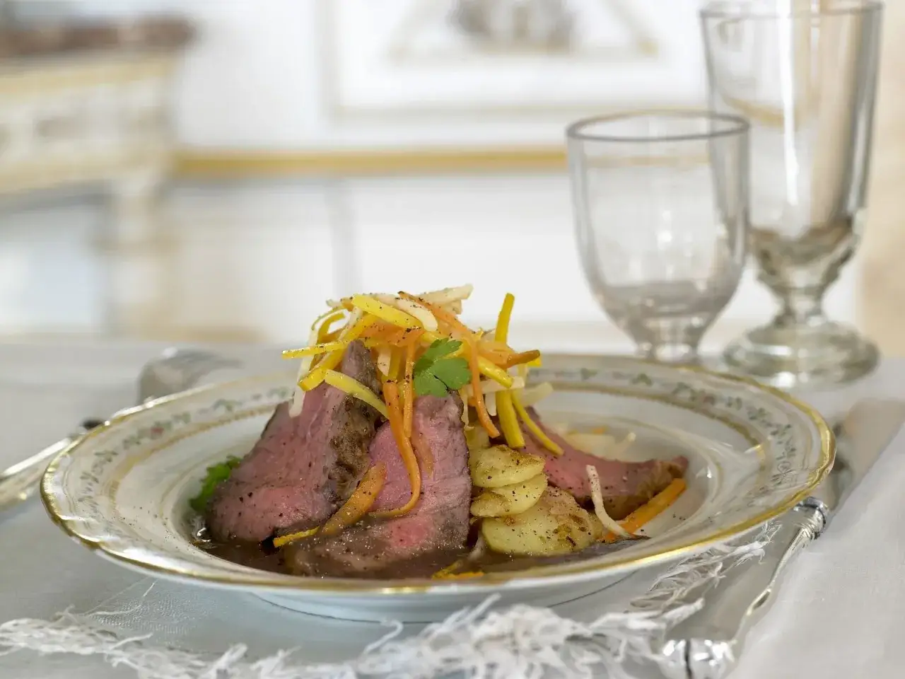 Zartes Roastbeef als Beilage, garniert mit julienniertem Gem&uuml;se und Kartoffelscheiben auf einem eleganten Teller.