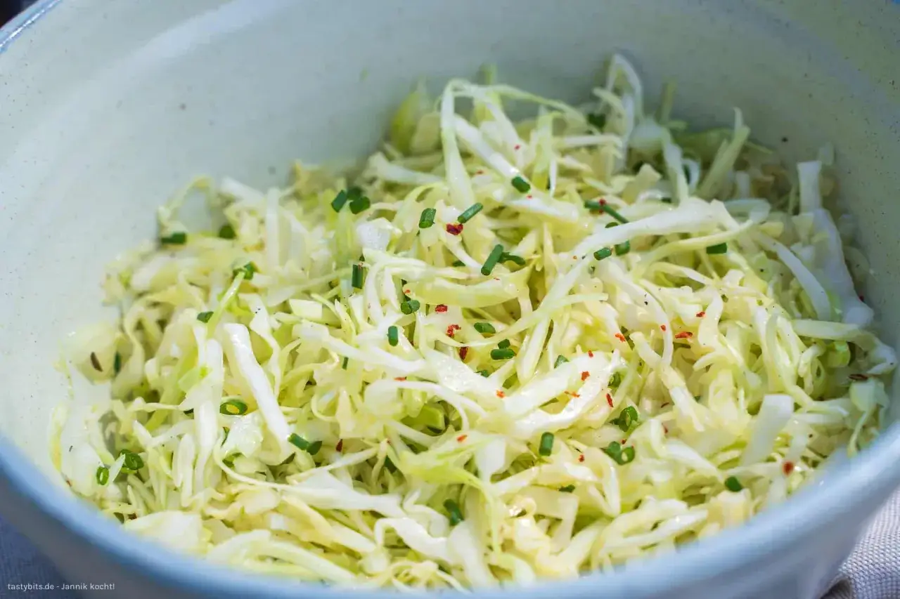 Frischer, fein geschnittener spitzkohl roh, garniert mit Schnittlauch und Chiliflocken, in einer Schüssel.