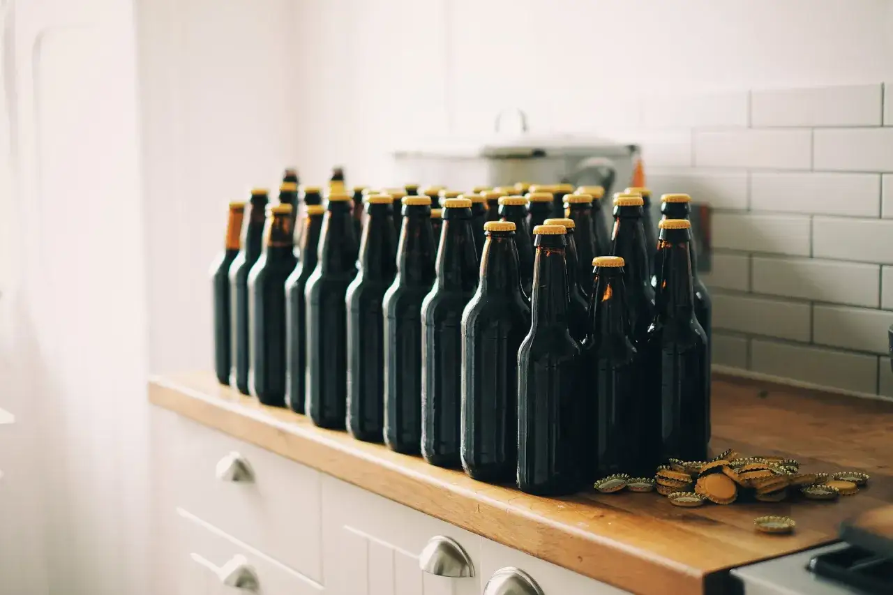 Reihe von dunklen Bierflaschen mit goldenen Kronkorken, bereit zum Bier lagern.