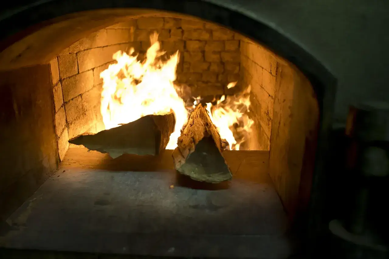 Flammen lodern in einem gemauerten Ofen. Holzscheite brennen, ein wichtiger Schritt bei der rauchbier herstellung.