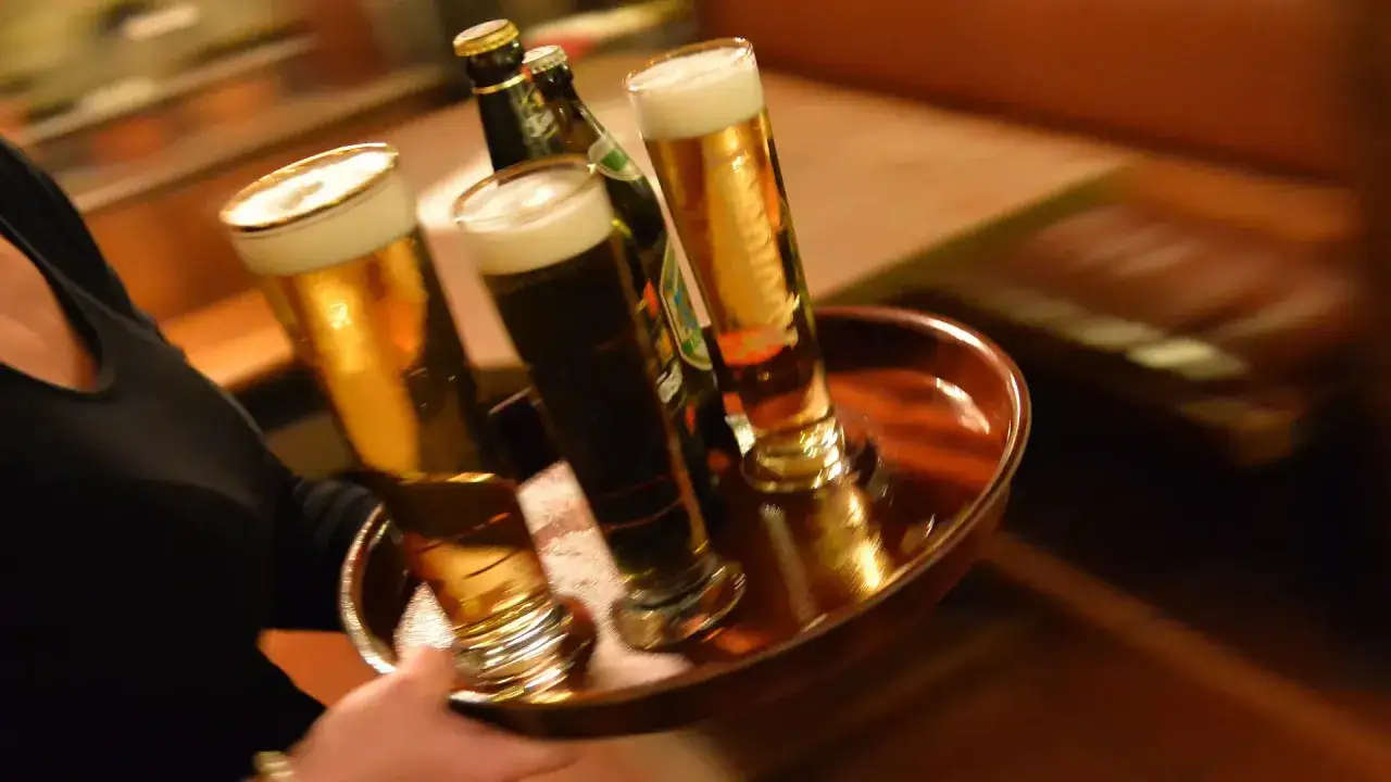 Kellnerin serviert Biergläser auf einem Tablett. Ein Genuss, der auch Bier Kalorien hat.